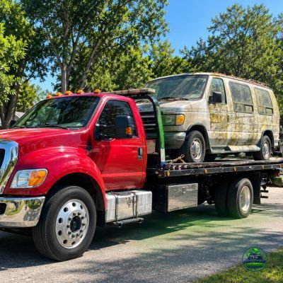 Tow truck transporting an old van for Cash Four Car Tampa junk car buying services.